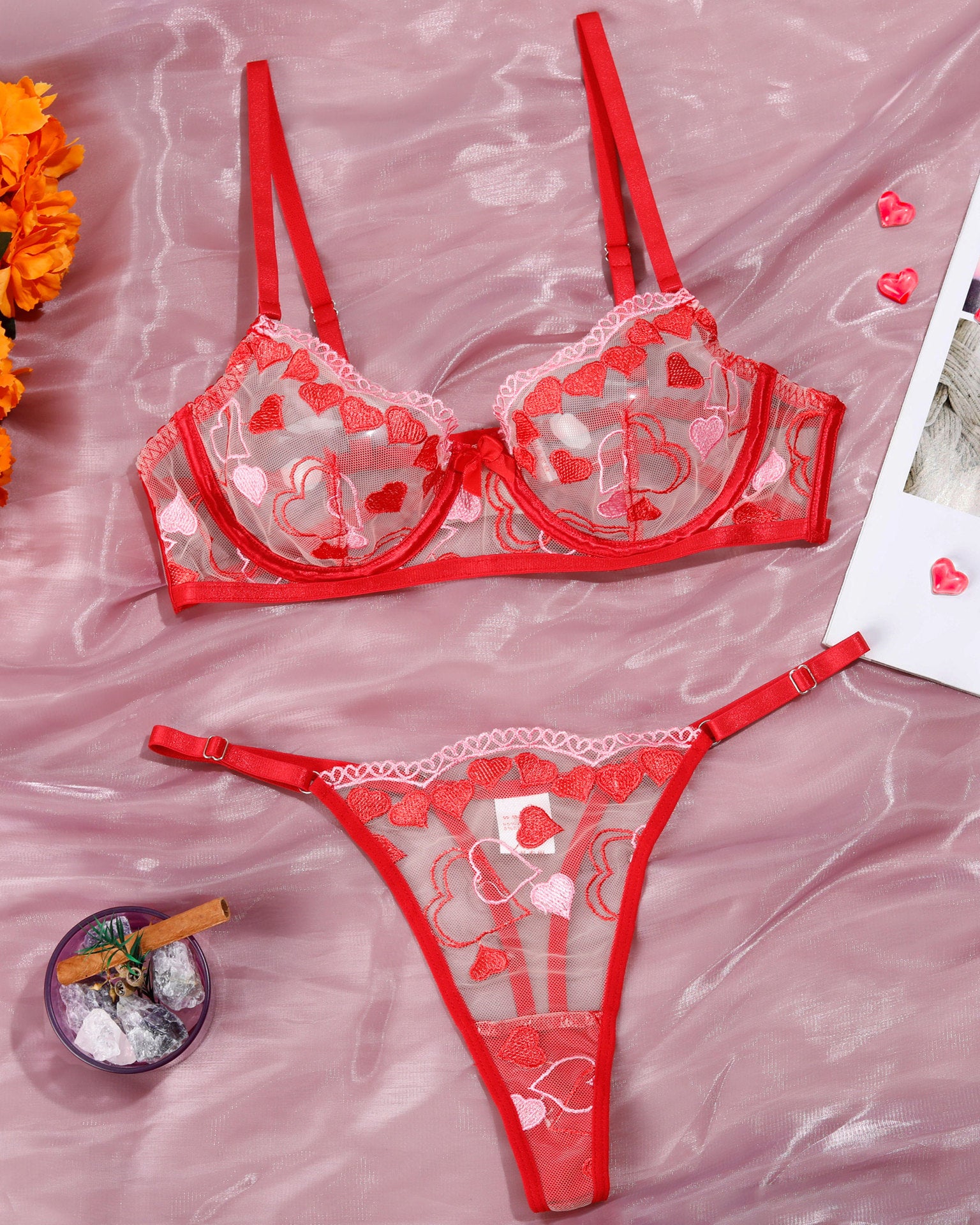Red lingerie set with heart decorations on a pink fabric background
