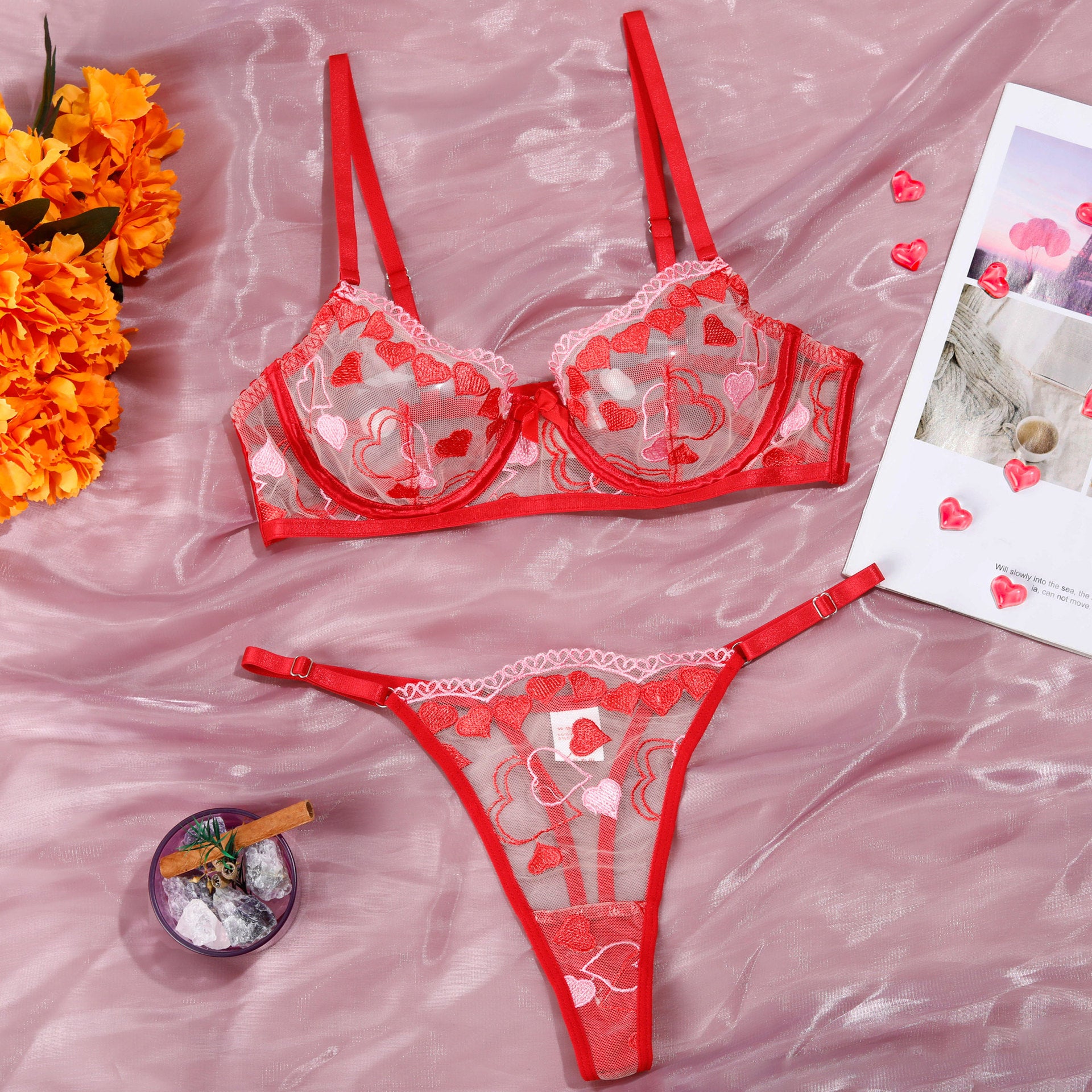 Red lingerie set with heart decorations on a pink fabric background