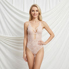 Woman wearing a pink lace lingerie set against a white draped curtain background