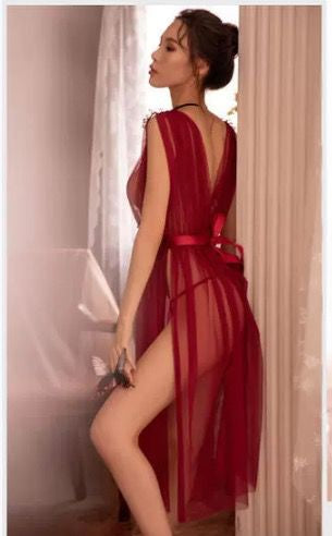 Woman wearing a red sheer dress in a softly lit room.