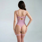Woman wearing a pink bodysuit and fishnet stockings on a plain background